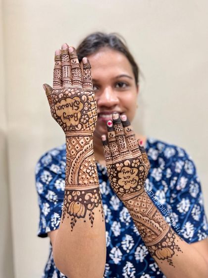 The happy mom-to-be showing off her baby shower mehendi. The design is elegant and celebratory.