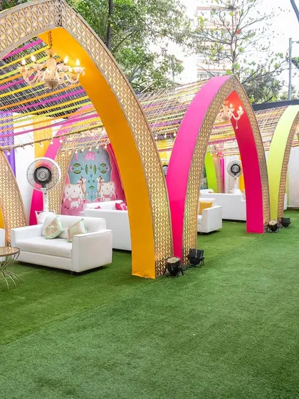 This outdoor lounge area was designed for a vibrant Garba night. We used a series of colorful arches with intricate gold lattice work and ribbon canopies to create semi-private seating zones, combining modern comfort with a festive, traditional atmosphere.