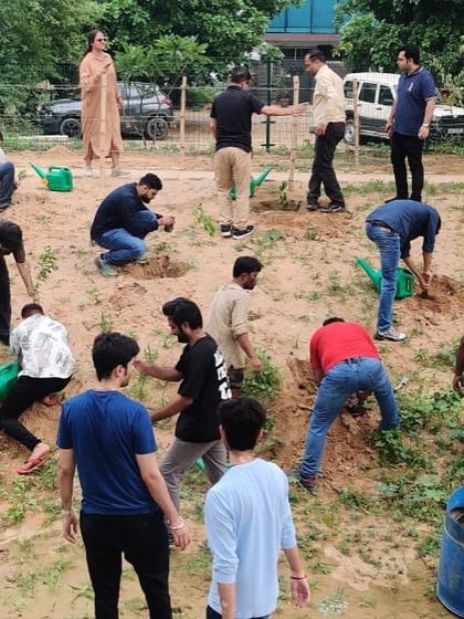 The Estee Advisors team works together in a heart shape formation to plant saplings, adding a touch of creativity to their green initiative.