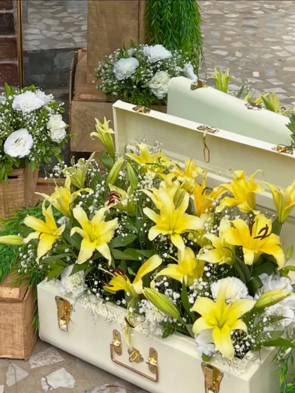 Thinking outside the box for floral displays. Here, a vintage white suitcase overflows with bright yellow lilies and baby's breath, creating a unique and memorable decor piece for the citrus themed shower.