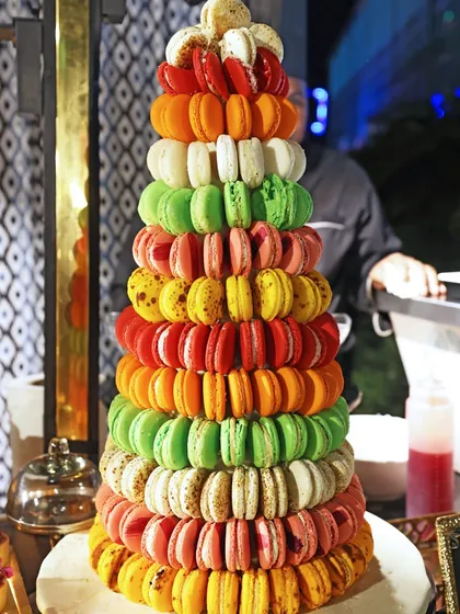 A vibrant, multi-coloured macaron tower stands as a cheerful and delicious centerpiece for a milestone birthday celebration.