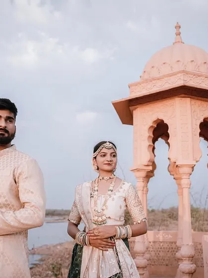 A wide shot that captures the couple, the palace architecture, and the natural landscape. This photo tells a complete story of romance in a grand setting.