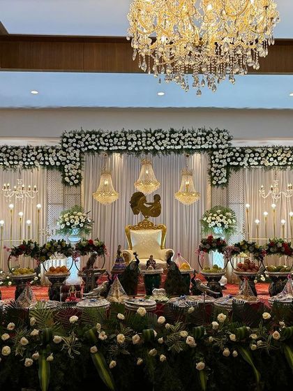 An elegant stage with white curtains, chandeliers, and a rooster motif on the throne.