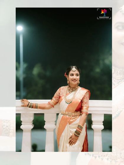A classic bridal portrait taken at night on a balcony. The bride's white saree and happy smile are beautifully illuminated, creating a timeless image.