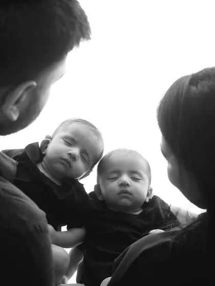 A creative black and white shot of parents admiring their twin babies. The unique angle and monochrome style create a very artistic and emotional family portrait.