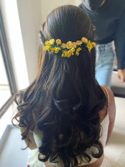 A perfect half-up, half-down hairstyle for a Haldi ceremony, decorated with pretty yellow flowers.