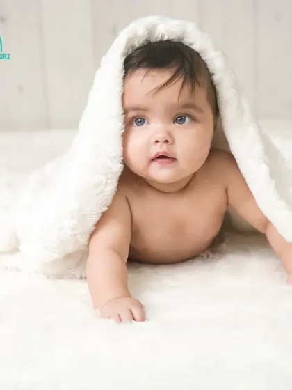 Peek-a-boo. This adorable twin is playing under a fluffy white blanket, her bright eyes looking right at the camera.