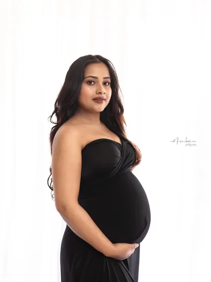 A direct and engaging portrait where the mother-to-be looks at the camera. Her confident expression and the simple, elegant styling make this a powerful and modern maternity photo.