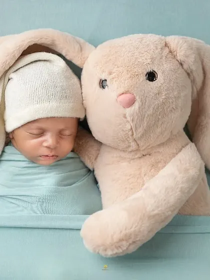 Sometimes the simplest concepts are the most heartwarming. Here, a sleeping baby in a soft knit hat snuggles with his first best friend, a plush bunny, creating a dreamy and gentle newborn portrait.