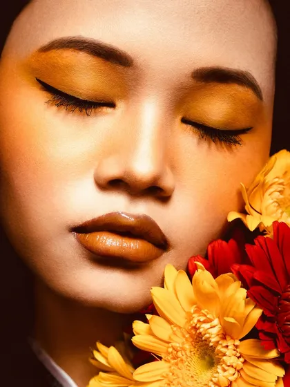 A close-up on the sunflower-inspired look, showing the blend of warm eyeshadow, glossy lips, and the contrast with fresh flowers. It's a celebration of natural, golden-hour glam.