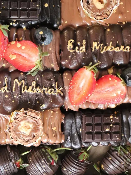 A close-up of my Eid chocolate slab cake, decorated with fresh strawberries, blueberries, and "Eid Mubarak" in gold script.