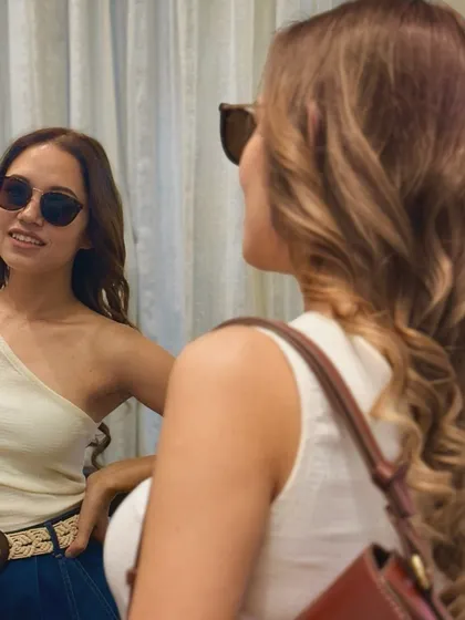 A closer look at a client's reflection as she admires her new hair. The sunglasses add a cool vibe, but the star of the show is the beautifully styled, healthy-looking brown hair.