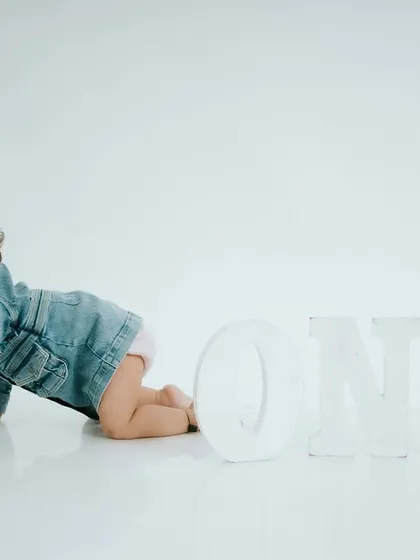 On the crawl. A minimalist setup with a clean white background and a 'ONE' prop is perfect for capturing your baby on the move.