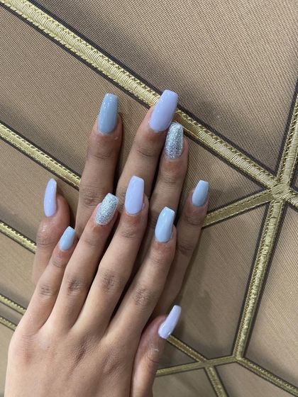 A cool and refreshing color combination. This client chose a lovely pastel blue for her square-shaped nail extensions, with two accent nails covered in sparkling silver glitter to add some fun and texture.