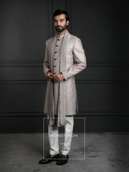 A champagne-beige sherwani in textured jacquard. Tailored in a sleek straight cut with classic buttons and a bandhgala collar, it’s understated elegance with regal finesse.