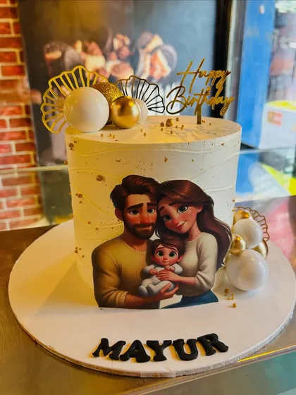 A lovely family portrait cake, featuring an edible image of a couple with their baby, decorated with elegant gold and white spheres.