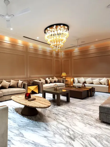This expansive living room showcases our commitment to opulence and scale. We used Italian marble flooring to create a reflective, bright surface, while the grand chandelier and layered wall paneling add warmth and sophistication.