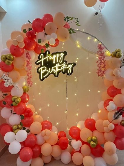 A beautiful balloon ring in peach, red, and white, with a neon sign and fairy lights.