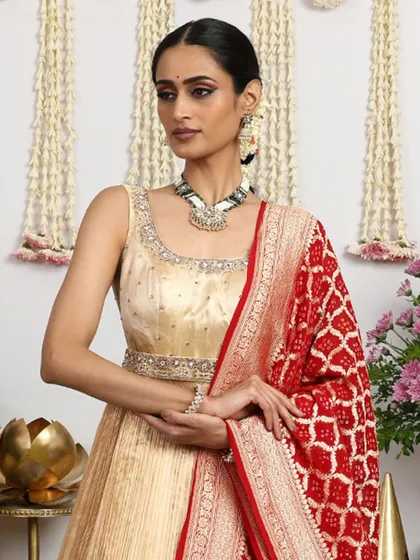 A close-up of the simple yet elegant sleeveless gold blouse, paired with a statement necklace.