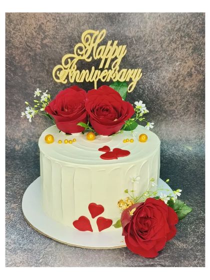 A romantic anniversary cake with fresh red roses and gold accents. This is a roasted almond chocolate mousse cake, offering a rich and nutty flavor.