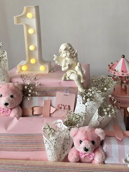 Celebrating a first birthday with this angelic pink hamper, featuring a light-up number '1', a miniature carousel, and sweet pink teddy bears.
