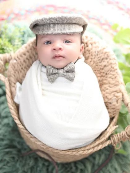Dressed like a little gentleman with a flat cap and bow tie, this baby is wide awake. His expressive eyes are the clear focus of this charming portrait.