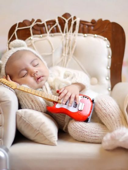 A close-up on our little beach musician, capturing a peaceful moment in the miniature armchair. We ensure every pose is safe and comfortable for the baby.