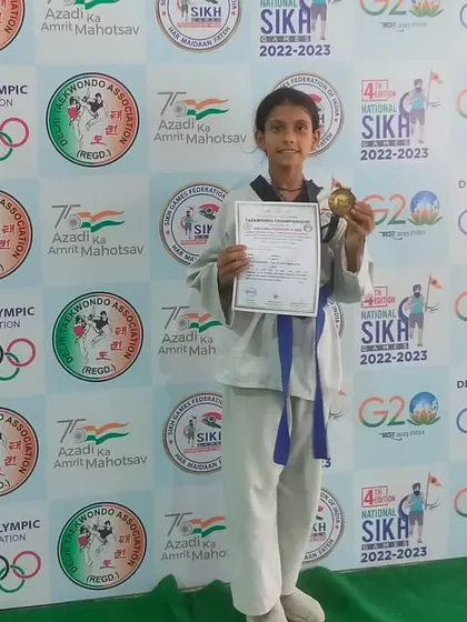 A young champion proudly holds her gold medal and certificate at the National Sikh Games.