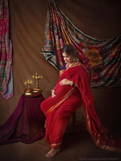 Inspired by the timeless paintings of Raja Ravi Varma, this portrait captures the divine grace of motherhood. The rich red saree, antique brass lamps, and dramatic lighting come together to create a piece of heritage art.