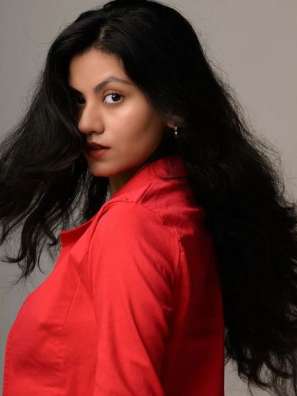 A bold and energetic studio shot. The combination of the red blazer and direct gaze creates a high-impact image that is perfect for a fashion-forward portfolio.