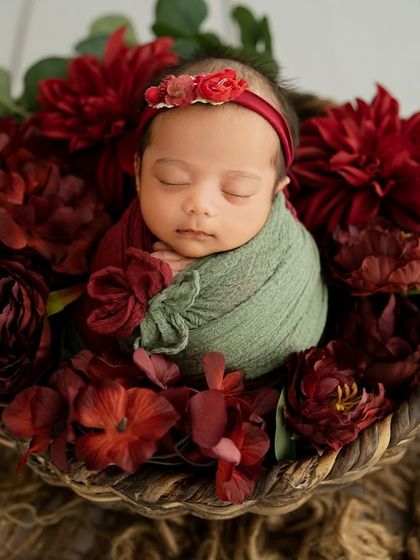 This overhead shot shows the full floral arrangement, creating a beautiful frame around the sleeping baby. The textures of the basket and flowers add depth to the portrait.