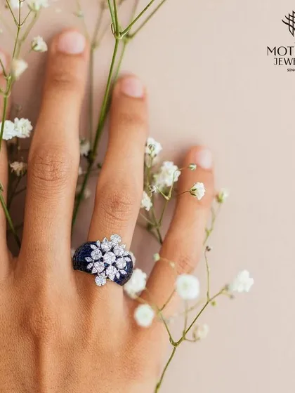 A beautiful composition of a hand wearing a floral diamond and sapphire ring, gently holding baby's breath flowers, evoking a sense of delicate luxury.