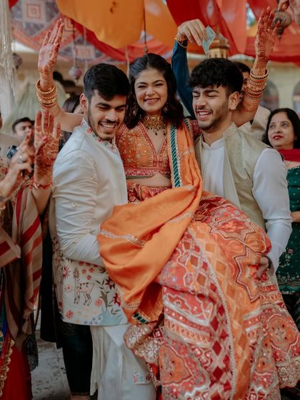 The bride's joyful entry for her Mehendi, surrounded by friends and family. The colorful decor in the background perfectly matches the happy vibes.