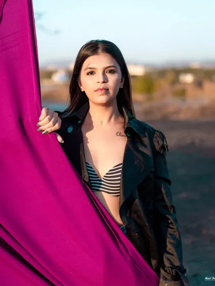 A high-fashion outdoor shot using a vibrant pink cloth. The contrast between the edgy outfit and the flowing fabric creates a visually striking image.
