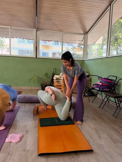 Assisting a student in a deep quad stretch. This image shows how we teach you to use your body weight and positioning to provide stable support, allowing the student to relax and find more depth in the pose.