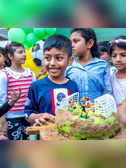 The birthday boy and his friends gather around the amazing football cake, ready to sing and celebrate.