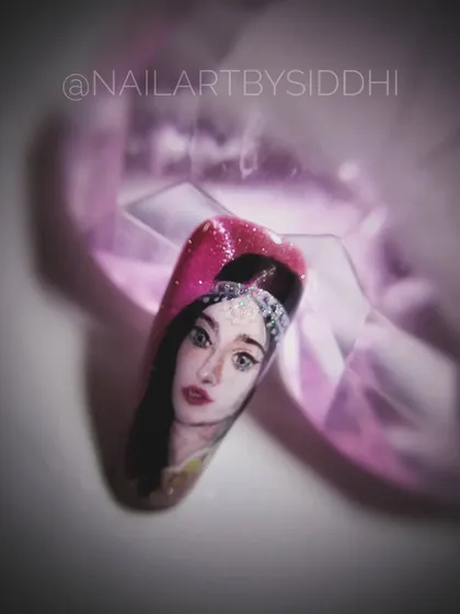 A close-up of the Adah Sharma portrait nail, highlighting the detail against a sparkling pink background.