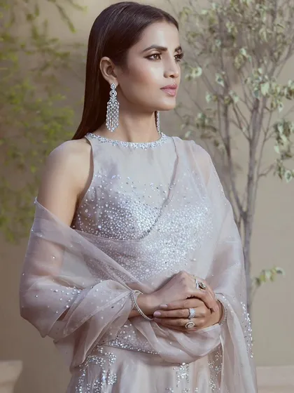 This portrait-style campaign shot highlights the intricate beadwork on the blouse and the sheer fabric of the dupatta. The focus is on the texture and detail that make this designer piece special.