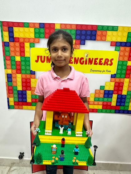 A girl presents her detailed LEGO pandal, complete with a green lawn, miniature figures, and street lamps.