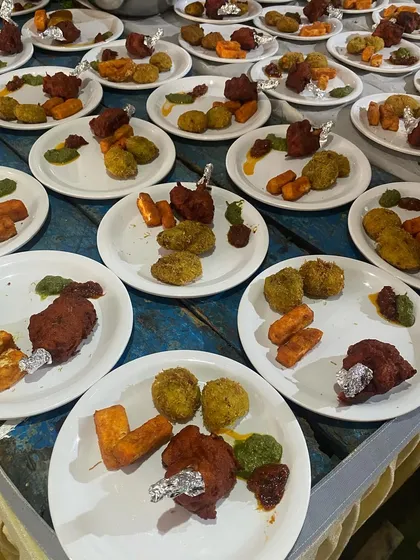 Plates of assorted starters ready to be served to guests, featuring chicken lollipops and veg cutlets.