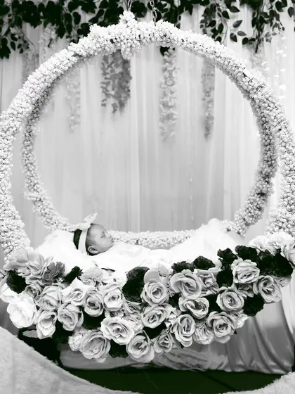 The naming ceremony is all about the little one. This artistic photo shows a newborn resting peacefully in a circular floral cradle I designed, highlighting how my decorations create beautiful and tender photo opportunities.