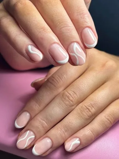 A creative take on the French manicure, featuring abstract white swirls on the tips. This design offers a unique, artistic alternative to the traditional straight line.