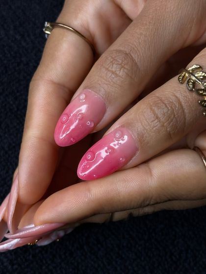Adding depth and texture is a key skill. This close-up shows 3D water droplet effects on a pink ombre base, a creative technique taught in our classes.