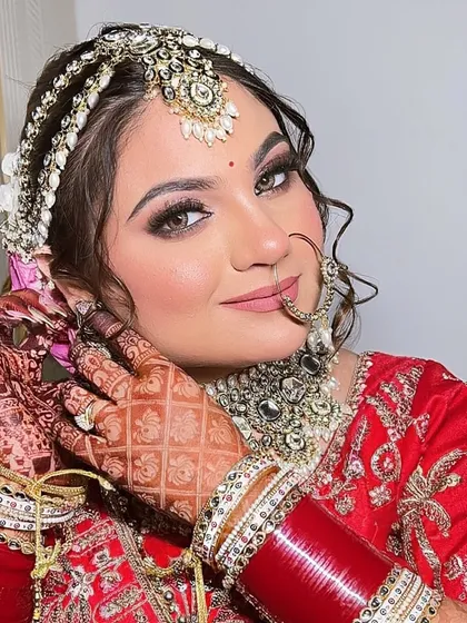 Adjusting her earring, Payal looks every bit the goddess. Her makeup features shimmery eyes and a soft pink lip, which perfectly complements her heavy kundan jewelry.