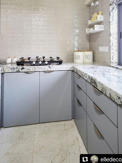 The kitchen in this home is clean, bright, and functional. Light grey cabinets and a simple tiled backsplash are paired with a granite countertop, reflecting the project's sophisticated and practical approach.