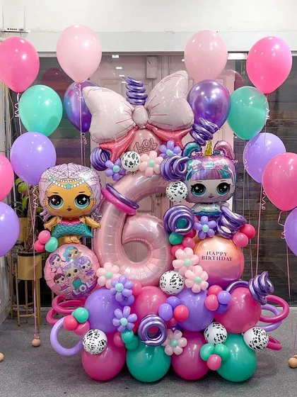 The complete LOL Dolls party package! This photo shows the main sculpture accompanied by floating helium balloons in matching colors, creating a full and festive party atmosphere.