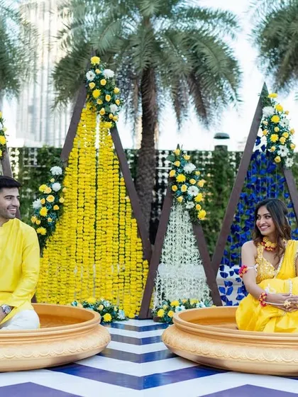 A modern and geometric Haldi setup. We used triangular backdrops with marigold strings and pops of blue for a fresh and contemporary take on the traditional ceremony.