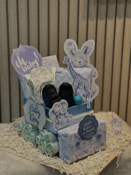 I love creating these diaper trolleys. This one for 'Baby Boy' is made with carefully rolled diapers and filled with essentials like baby shoes and soft toys.