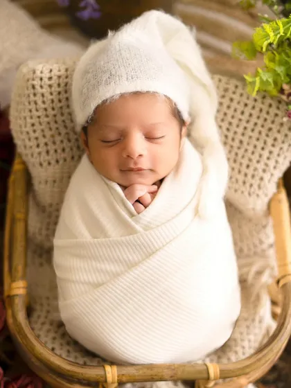 A sleeping angel with the sweetest smile. Wrapped in white with a sleepy hat, this newborn portrait is a memory to cherish forever.