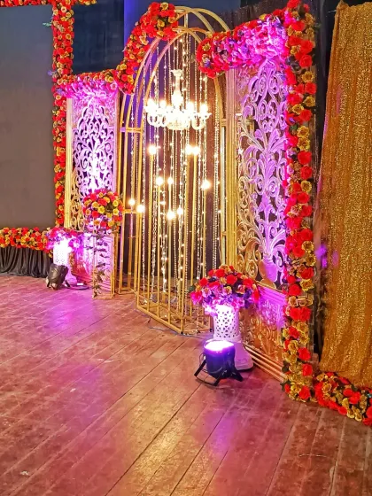 A detailed view of a selfie backdrop with intricate golden gates, red floral borders, and chandelier lighting, designed for guests to take memorable photos.